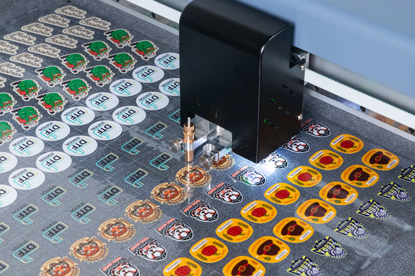 The cutting head of the Arc 127 over a sheet of printed stickers